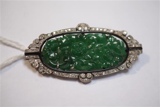 A 1920s/1930s Art Deco white gold?, pierced carved jadeite, diamond and black onyx set oval brooch, 53mm.